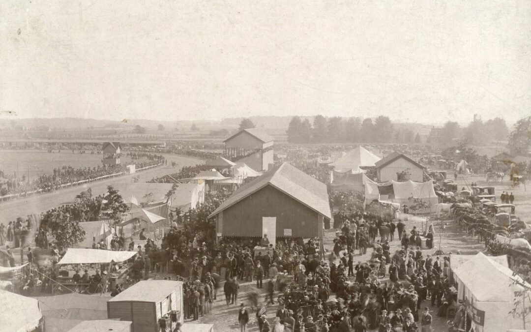 Birds eye view of large crowd amongst dirt track and buildings